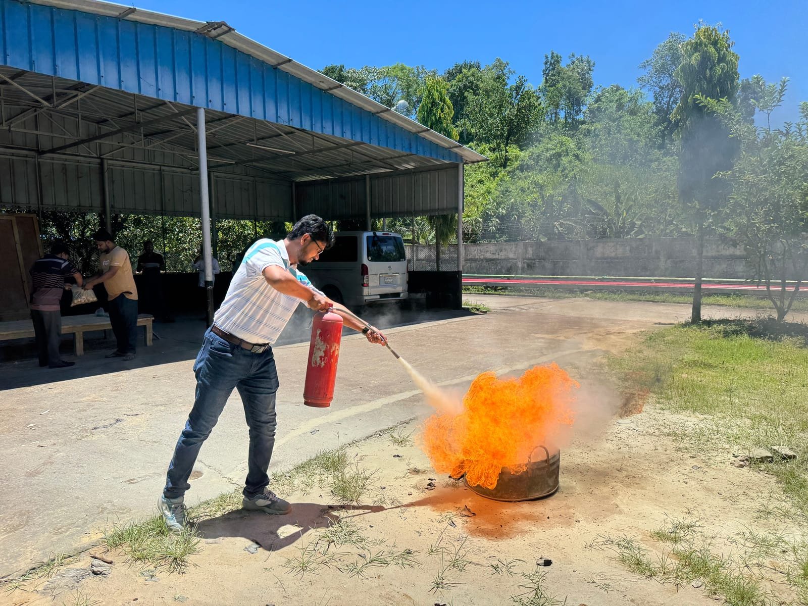A worker discharges a portable fire extinguisher onto a small controlled training fire in an open yard. Photo: Shutterbug Aminul, via Pexels