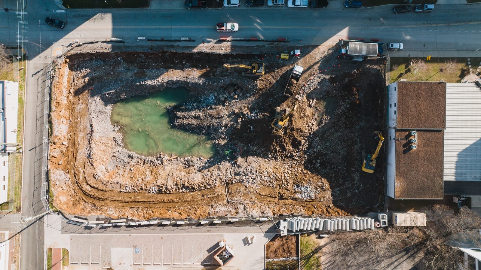Top-down drone view of an urban excavation site in Nashville, Tennessee, where several excavators and trucks work the same open pit beside a city street. Photo: K, via Pexels